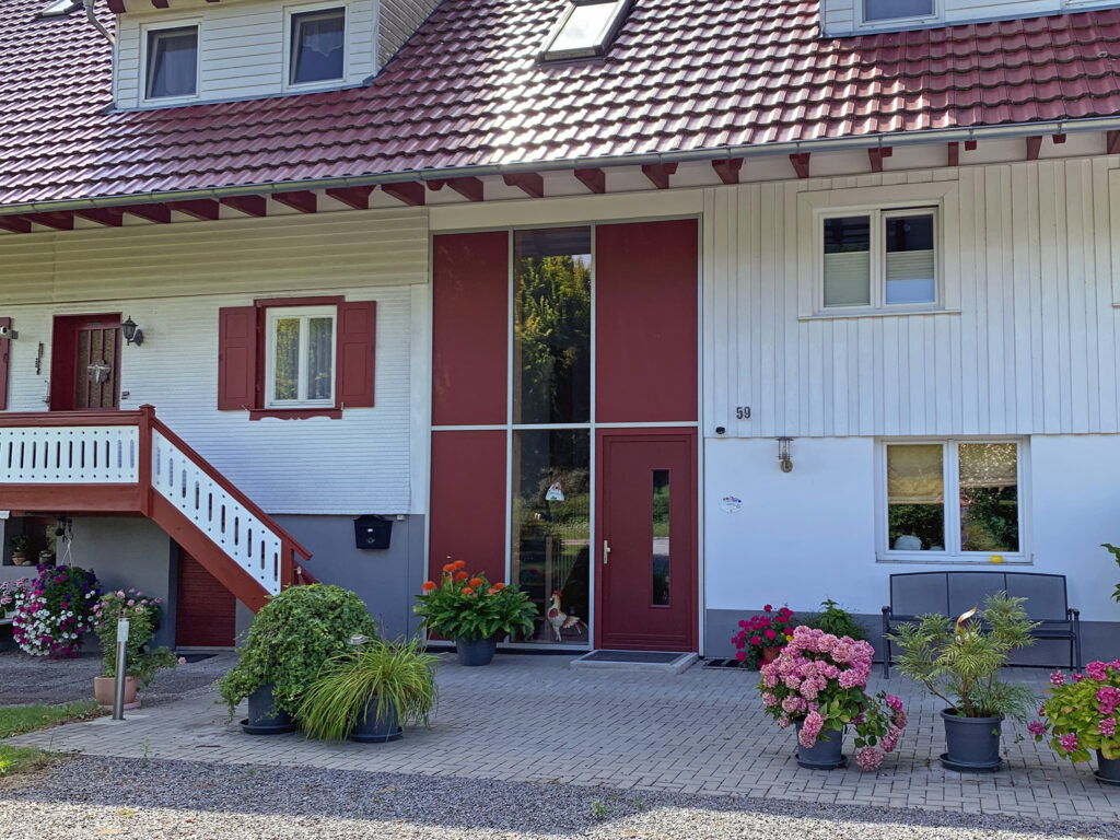 Außenaufnahme des Ferienhaus Zimmermann in Zell am Harmersbach. Es ist der große, verglaste Eingang der zu den Ferienwohnungen führt zu sehen.